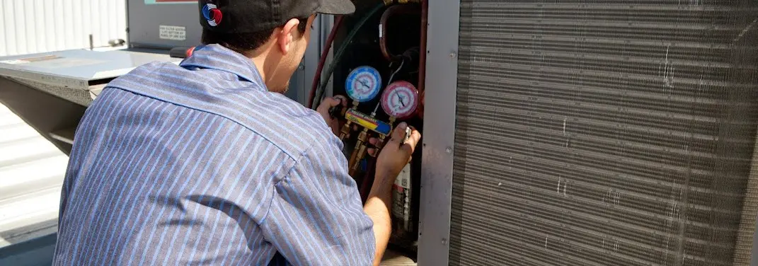 HVAC technician servicing a condenser unit in North Kensington
